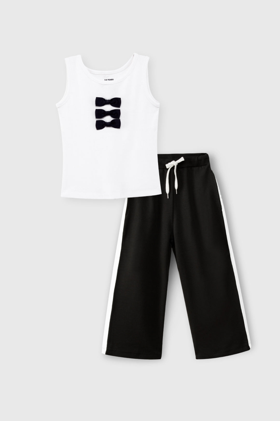 White tank top with black bow design and black pants on a white background